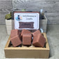 Brown Library soy wax melts in a wooden box with decorative rocks and product packaging for the Library wax melts.