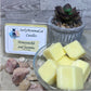 Yellow Honeysuckle and Jasmine soy cubed wax melts in glass bowl with product container, and decorative rocks and plants.