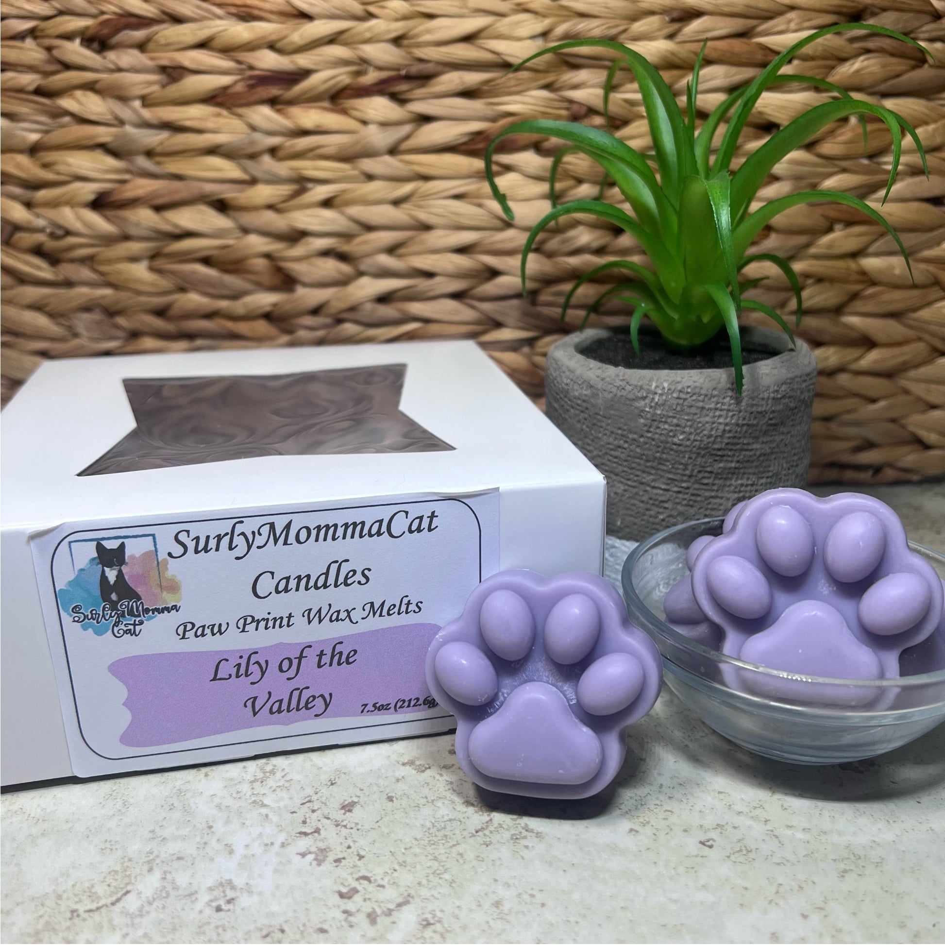 Light Purple Lily of the Valley Soy paw print wax melts in a glass jar, and in a box labeled Lily of the Valley, with small plants for décor.