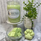 Light green soy Mint Mojito candle with cube wax melts in a glass bowl and pawprint wax melts, with a small plant for decor.