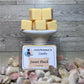 Tan Sweet Peach soy wax Melts cubes on a small white pedestal, with decorative rocks and wax melt box labeled Sweet Peach.